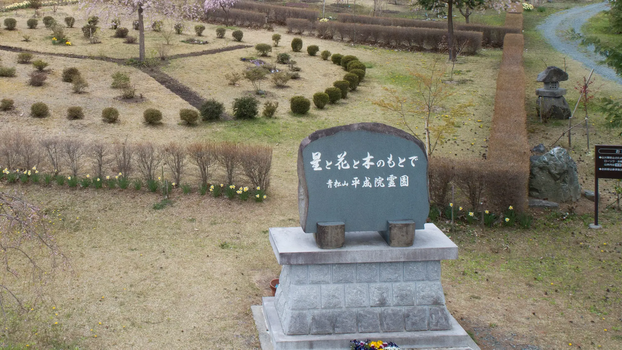 霊園の名を刻んだ石碑と、その奥に広がる境内